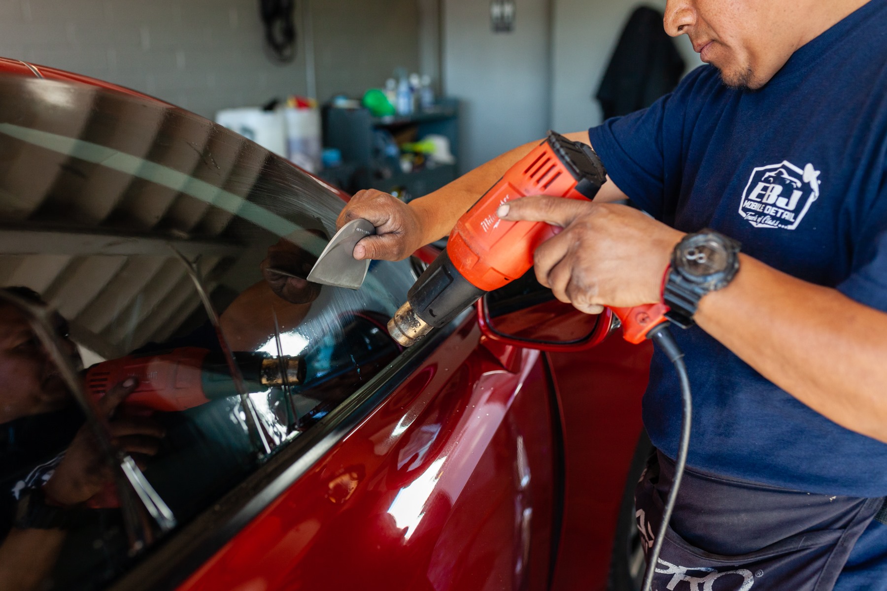 EBJ technician installing window tint on a red car