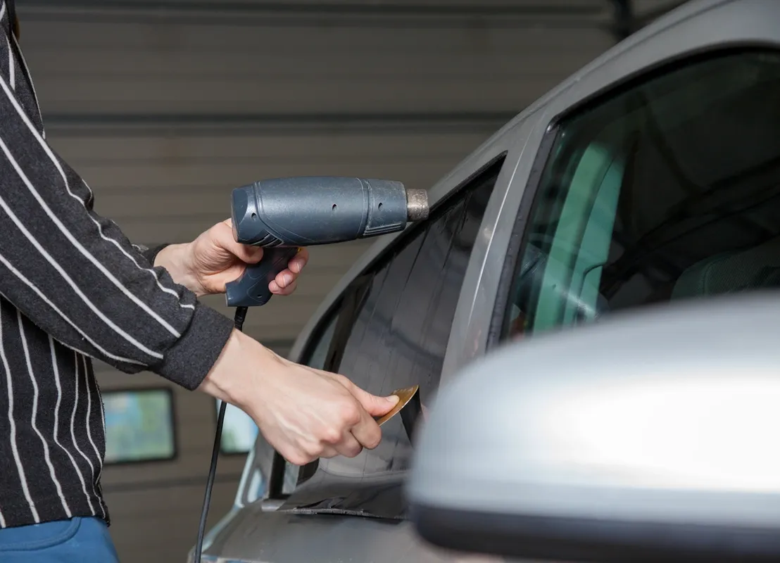 Heat gun shrinking tint film on a car window